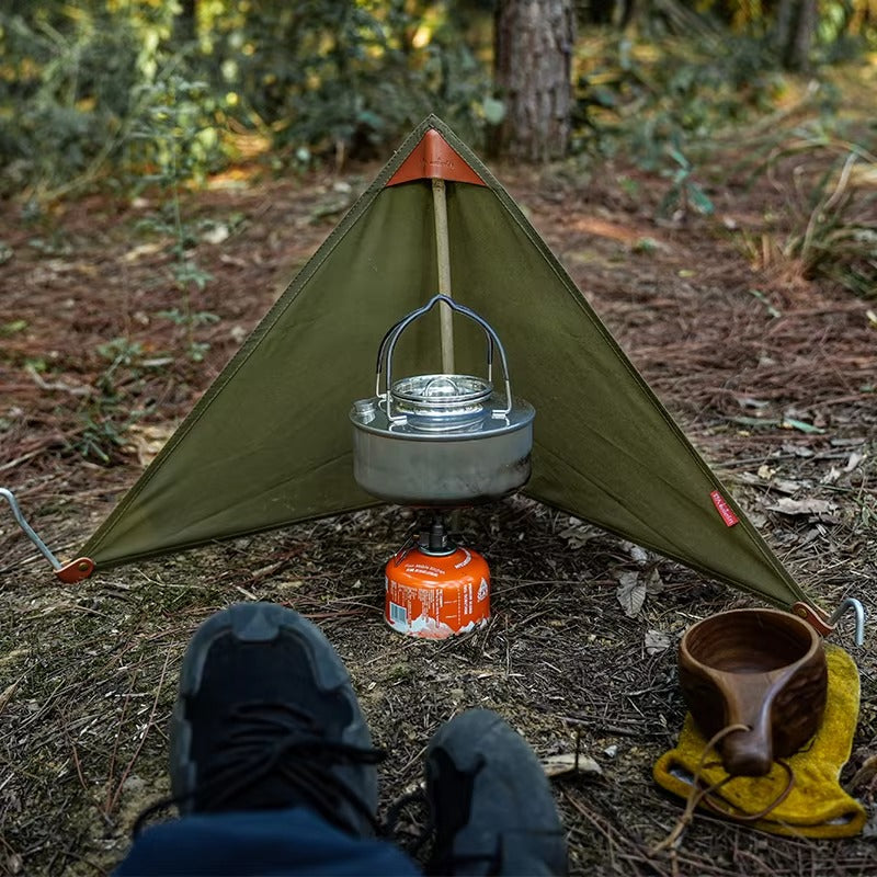 Green stove windshield set up around a camp stove and kettle